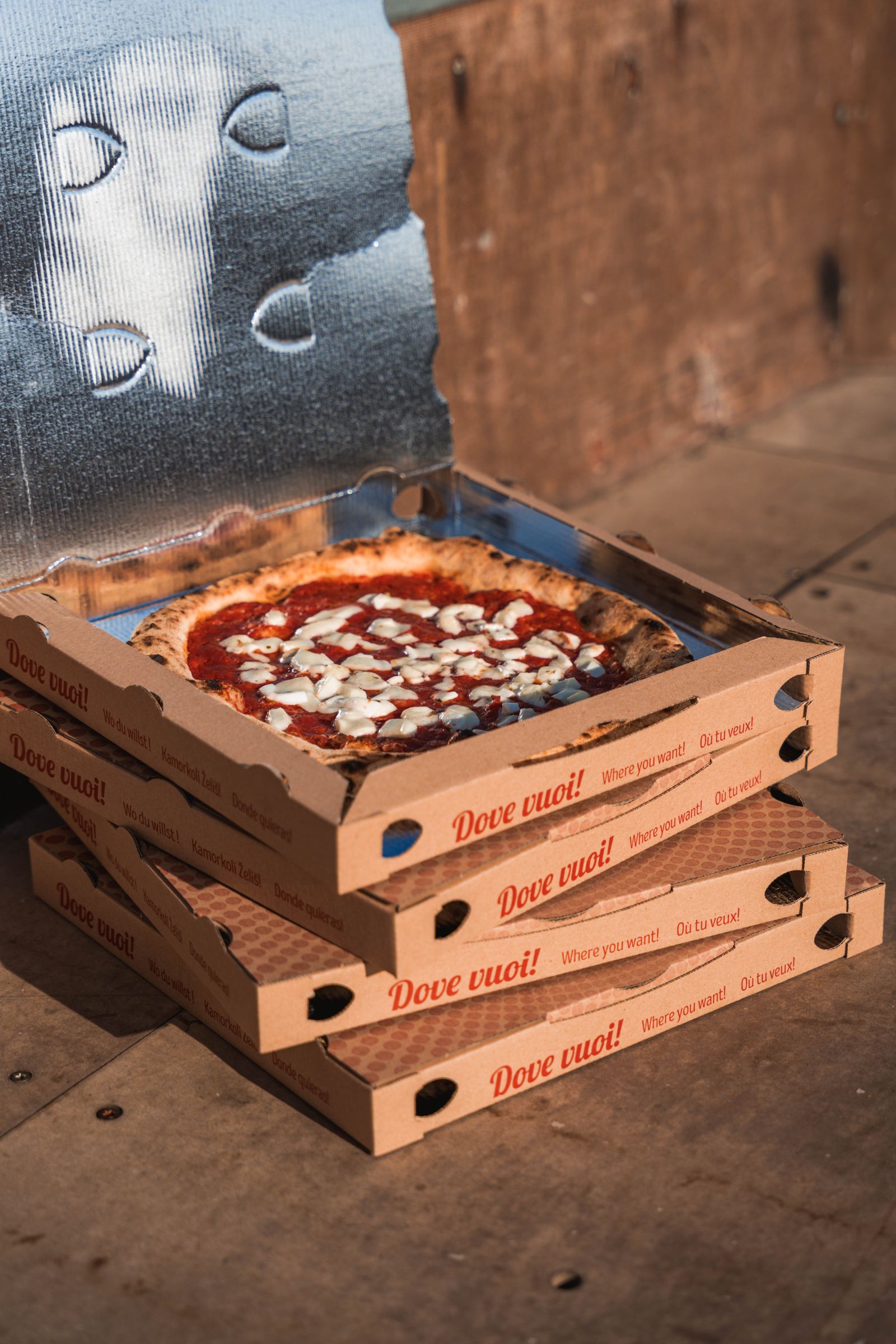 Pizza in einem geöffneten Karton auf gestapelten Pizzakartons
